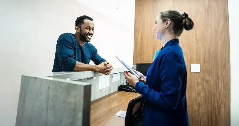 Medical office professional assisting a patient at the reception desk, illustrating a potential career in the Medical Office Administration program.